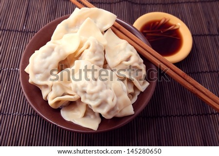 Bowl of cooked Chinese dumplings on bamboo mat