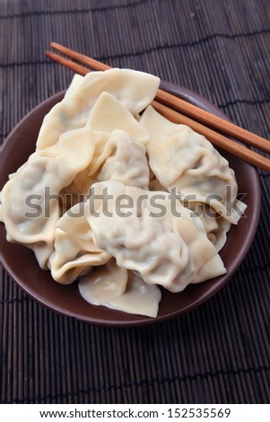 Plate of cooked Chinese dumplings on bamboo mat