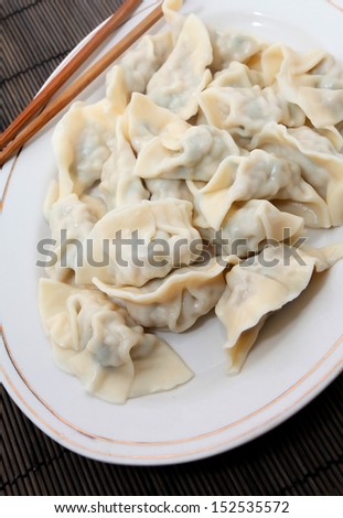 Plate of cooked Chinese dumplings on bamboo mat
