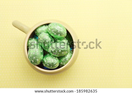 Easter chocolate eggs in the bowl over green background