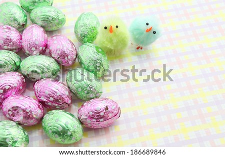 Colorful Easter chocolate eggs with little Easter chicken with colorful background
