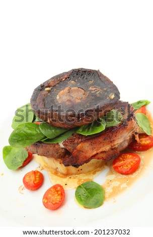 Big mushroom on the steak wrapped with bacon and vegetables