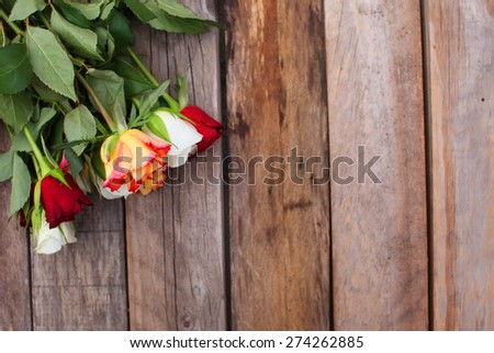 Red, white and shades of orange roses over wooden table background
