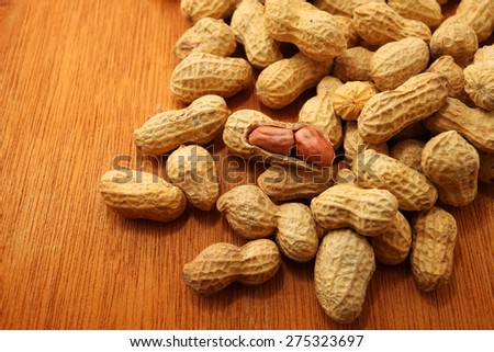 Peeled peanut and well peanuts over wooden table background