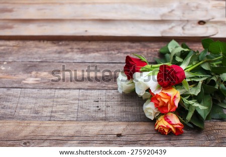 Red, white and shades of orange roses over wooden table background