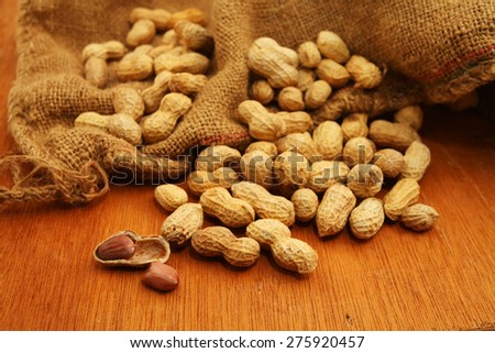 Peeled peanut and well peanuts over wooden table background