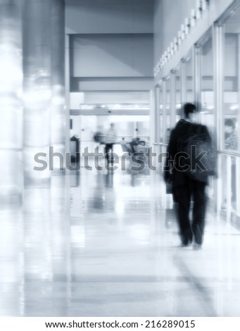 Modern contemporary architecture concept: silhouette of man walking through a gallery - interior of sparkling and splendent business building hall with columns.