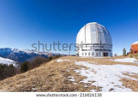 Special astrophysical observatory of Russian Academy of sciences located in mountain area. Tower od Big azimuth telescope serves as foreground. Surrounding mountains and blue sky serve as a background