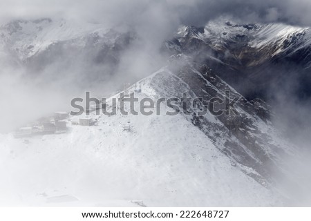 Snow-capped Elbrus mountain surrounded by clouds rises above the mountain area in Kabardino-Balkaria (Caucasus, Russia). Can be used as a background, wallpaper or postcard.