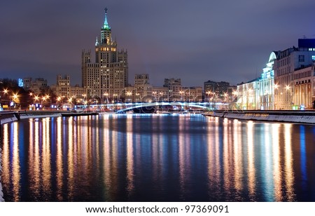 Moscow night: Moscow center (Russia) by winter night. Moskva river with streetlight reflected in water, embankment, bridge, high-rise building and and cloudy sky as a background.