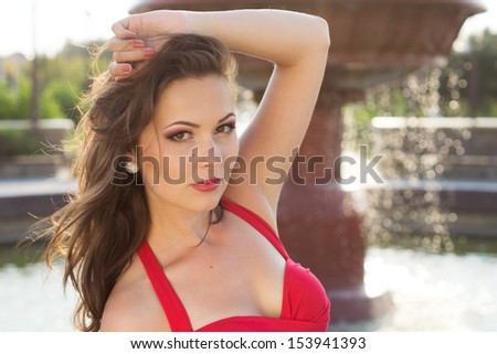 young beautiful brunette girl near water fountain in a hot day