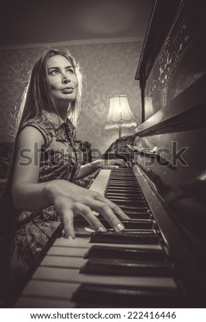 Portrait of beautiful young girl with long hair playing piano in interior. Musical instrument pianoforte with woman performer