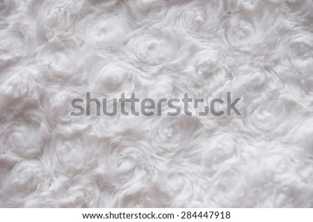 White curly faux fur texture background fragment, is generated from a material of clothes. Textured fabric background
