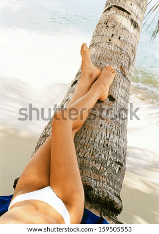 woman relaxing on tropical beach with feet resting