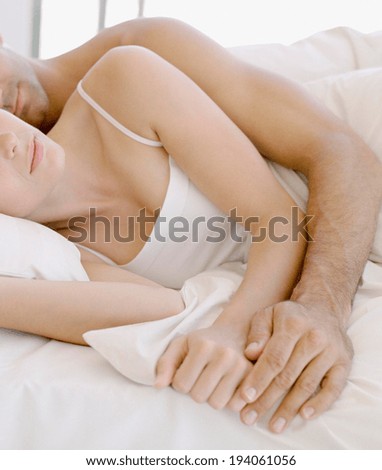 Woman sleeping peacefully on her husbands chest in bed