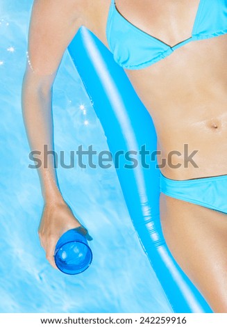 Young pretty woman with perfect tanned body lying on  air mattress in the pool