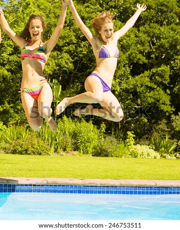 female friends jumping in pool at resort