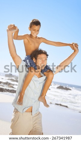 father and son holding hands while walking on sand at beach
