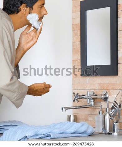 Portrait of smiling handsome shaving man in bathroom