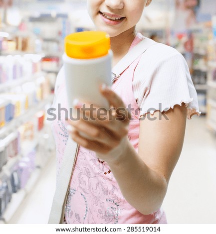 Young woman in the shop choosing shampoo