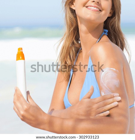 sexy young woman on the beach applying sun cream
