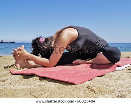 Yoga teacher practising at the beach janushirasana