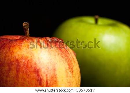 A red wet apple and a green apple on black background