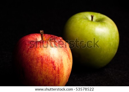 A red wet apple and a green apple on black background