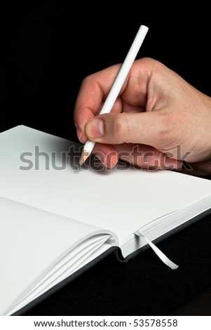 A hand writing with a white pencil on a blank white book