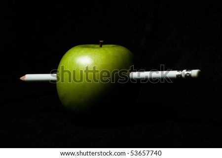 Green apple with a white pencil inside on black background