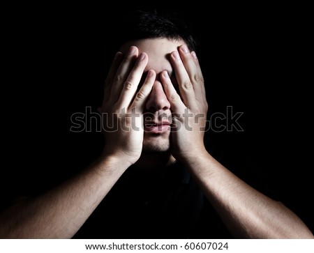 Dramatic portrait of young depressed man on black background