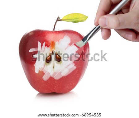 Male hand painting a red fresh apple revealing the inside