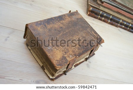 An old Bible covered in calf leather, more old books in the background