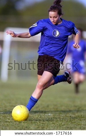 Teen Girl soccer player is about to kick yellow soccer ball