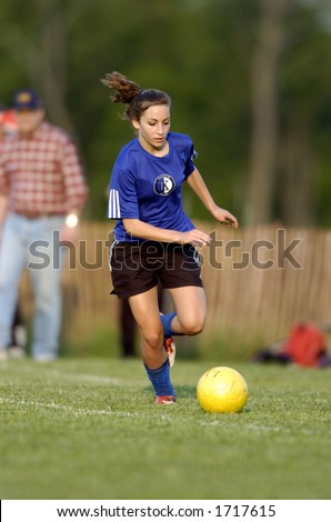 Teen Girl soccer player runs after yellow soccer ball