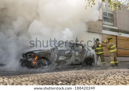 DISTRITO FEDERAL, MEXICO- JANUARY 22: Two firemen coordinate efforts between them as to be sure a still burning car is completely extinguished as seen in Mexico city on January 22, 2014.
