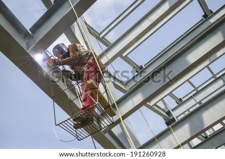 Welding metal columns Welder soldering metal girders in a structure high above