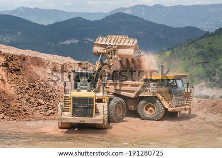Excavator working with dump truck Mining trucks working side by side to uncover precious metals in an open mine