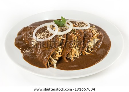 Mexican \'Mole\' Enchiladas isolated This enchiladas where made by a Mexican chef using exquisite \'mole\' sauce from the state of Puebla. They are served only with onion rings and sesame seeds.