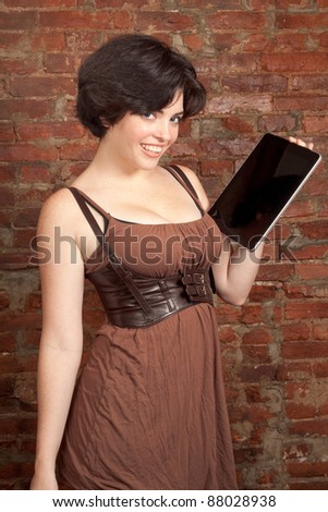 Brunette woman holding new electronic tablet touch pad computer pc and thinking about idea, one hand touches the digital screen