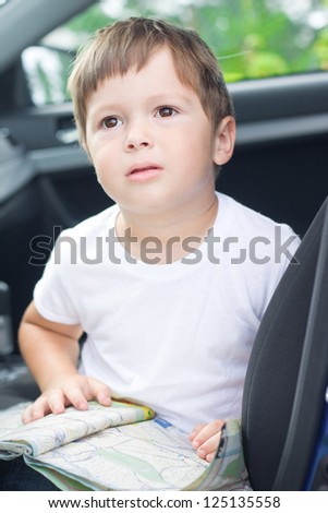 Boy with road map sits in car