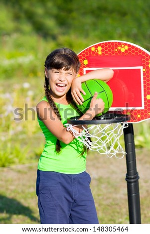 Teen girl with basketball shows thumb up