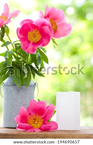 Pink peonies in metal vase and empty card for letter