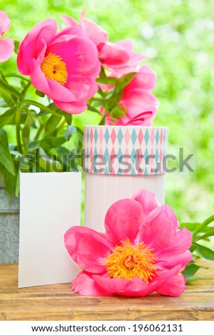 Pink peonies in metal vase, gift and empty card for letter