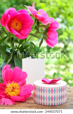 Pink peonies in metal vase, gift and empty card for letter