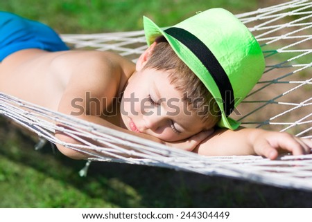 happy boy sleeps in hammock at garden