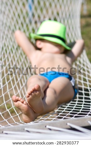 happy boy sleeps in hammock at garden. Focus on feet
