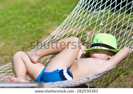 happy boy sleeps in hammock at garden. Focus on hat