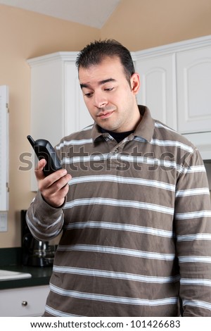 Young man holding a cordless phone handset in his hand with an annoyed or skeptical expression on his face.
