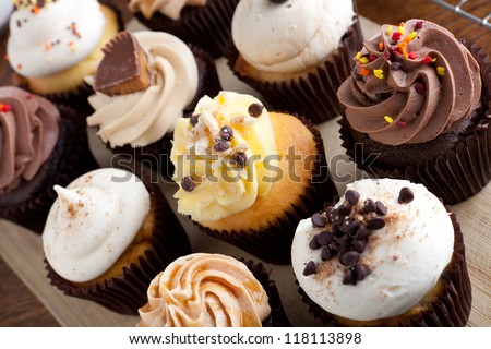 Close up of some decadent gourmet cupcakes frosted with a variety of frosting flavors.